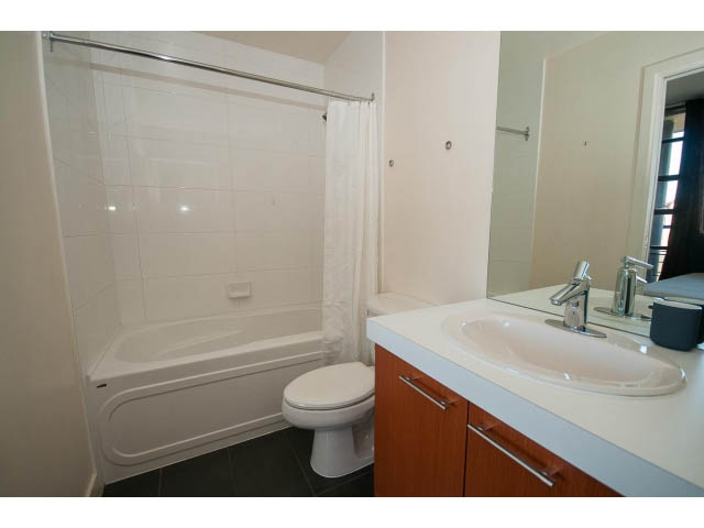Bright bathroom with white fixtures and wooden cabinets. - 401 - 2828 Yew St, Vancouver West Side