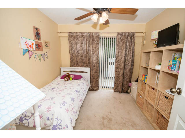 Bright bedroom with twin beds, floral bedding, and built-in shelving. - 2346 Riverbank Place, North Vancouver