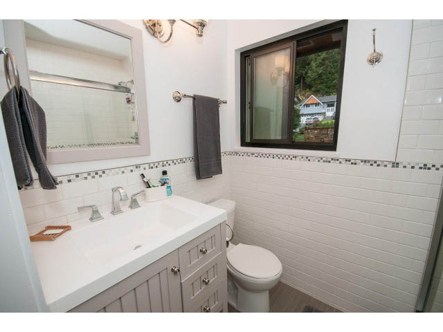 Small bathroom with white vanity, toilet, and window view of trees. - 2346 Riverbank Place, North Vancouver