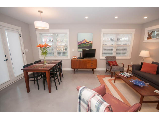 Bright living room with cozy furniture and a cityscape painting. - 2 - 217 East 19th, North Vancouver