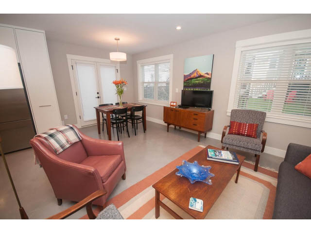 Bright living room with cozy furniture and a mountain painting. - 2 - 217 East 19th, North Vancouver