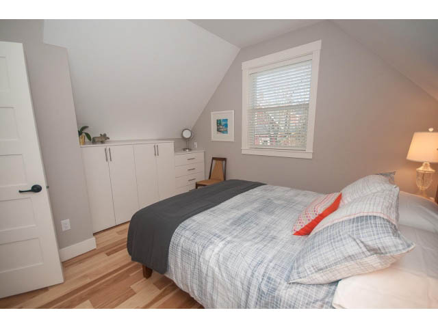 Bright bedroom with hardwood floors, city view, and neatly made bed. - 2 - 217 East 19th, North Vancouver