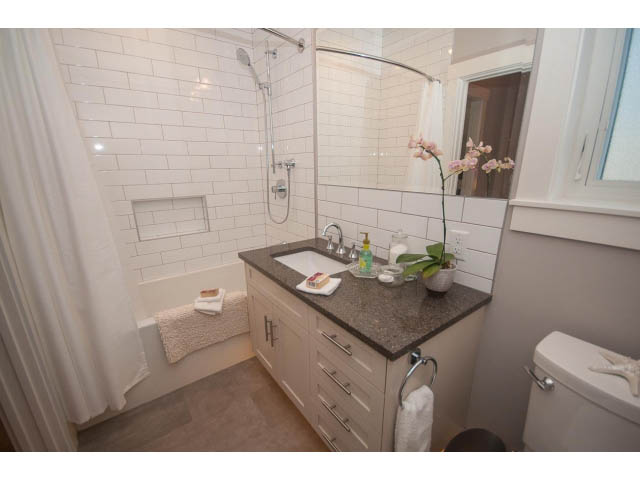 Bright bathroom with white subway tile, granite countertops, and a modern shower setup. - 2 - 217 East 19th, North Vancouver