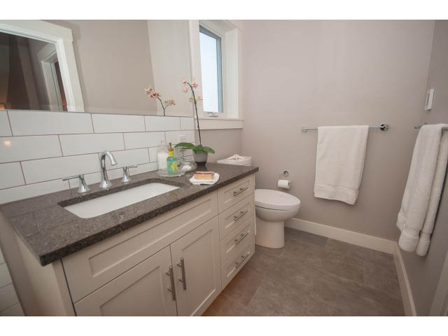 Bright bathroom with granite countertops and white cabinetry. - 2 - 217 East 19th, North Vancouver