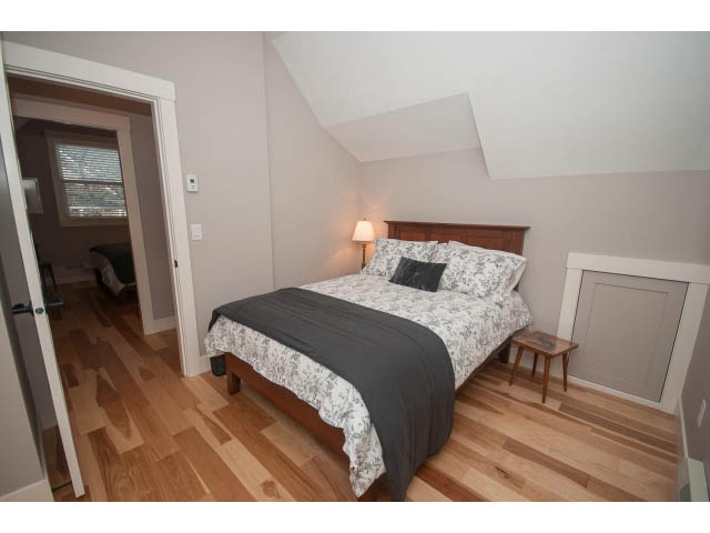 Spacious bedroom with hardwood floors and a cozy bed setup. - 2 - 217 East 19th, North Vancouver