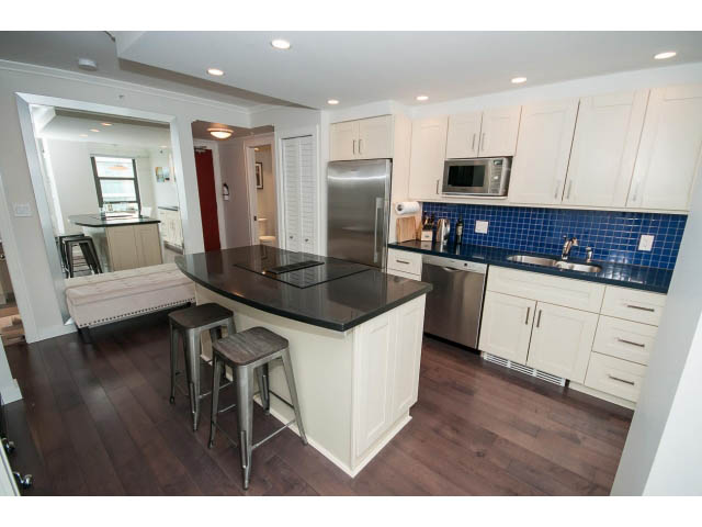Bright kitchen with dark wood floors, stainless steel appliances, and a blue tile backsplash. - 2407 - 1723 Alberni, Vancouver Downtown