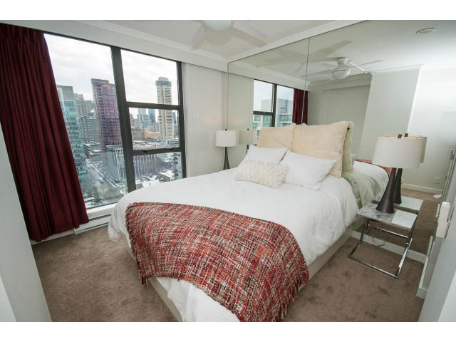 Spacious bedroom with mirrored wall, city view, and cozy bedding. - 2407 - 1723 Alberni, Vancouver Downtown