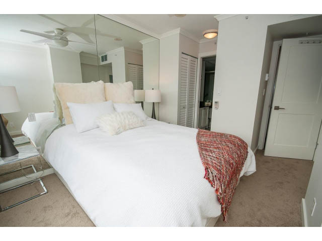 Bright bedroom with white bedding, mirrored closet, and carpeted floor. - 2407 - 1723 Alberni, Vancouver Downtown