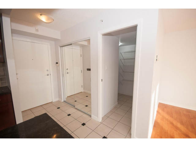 Bright kitchen with black countertops and hardwood floors, leading to a den area with sliding glass doors.