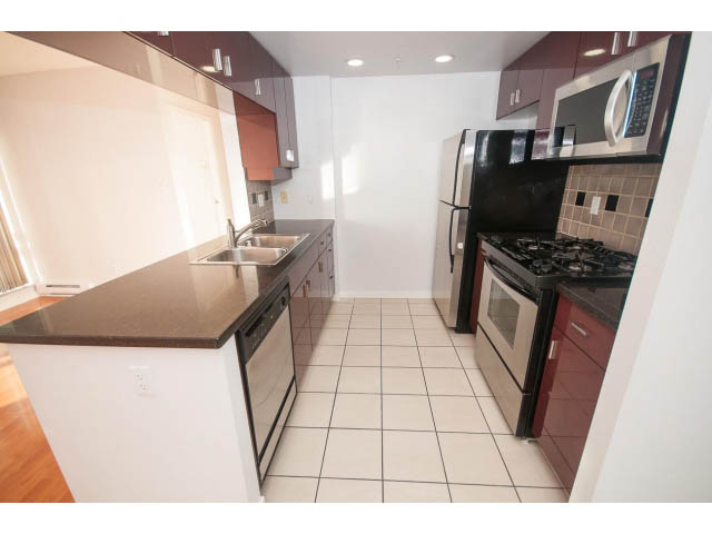 Bright kitchen with dark countertops, hardwood floors, and a modern stove. - 2005 - 1067 Marinaside Crescen, Vancouver Downtown