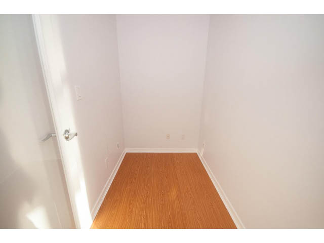 Bright hallway with hardwood floors and white walls leading to a door. - 2005 - 1067 Marinaside Crescen, Vancouver Downtown