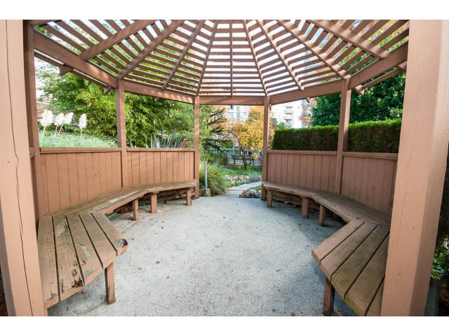 Furnished patio with wooden benches and a covered pergola, surrounded by greenery. - 2005 - 1067 Marinaside Crescen, Vancouver Downtown