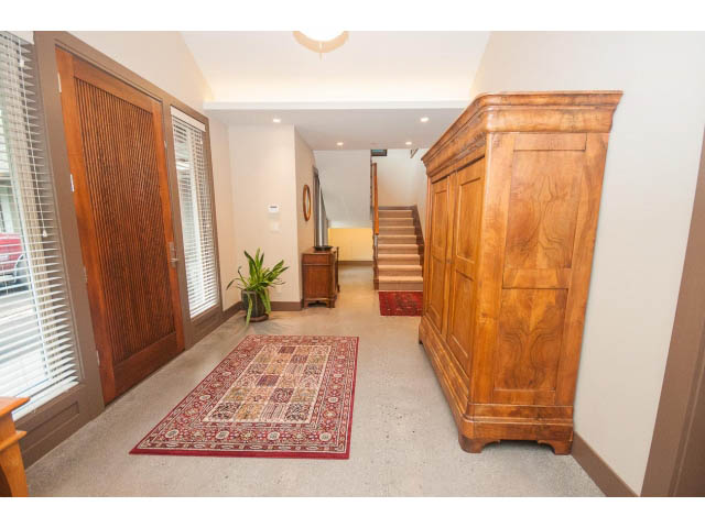Foyer with wooden staircase, red rug, and large windows. - 5070 Marine Drive, West Vancouver