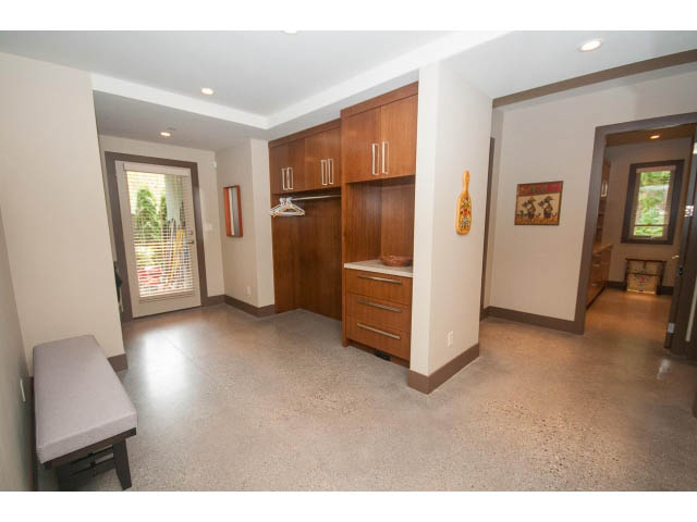 Bright kitchen with wooden cabinets, white countertops, and a city view through the door. - 5070 Marine Drive, West Vancouver