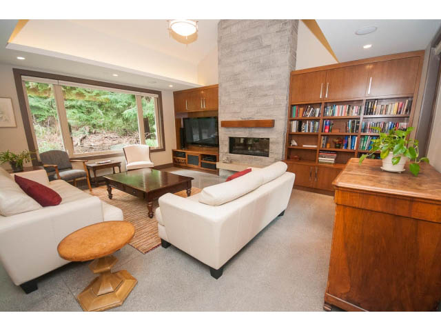 Spacious living room with fireplace, bookshelves, and large windows. - 5070 Marine Drive, West Vancouver