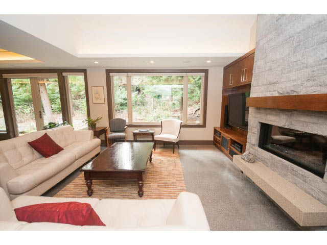 Spacious living room with large windows, modern fireplace, and comfortable seating. - 5070 Marine Drive, West Vancouver