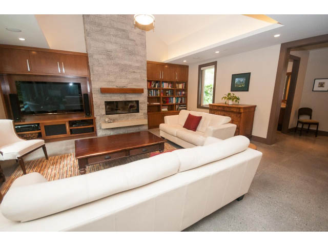 Spacious living room with modern furniture, large TV, and bookshelf. - 5070 Marine Drive, West Vancouver