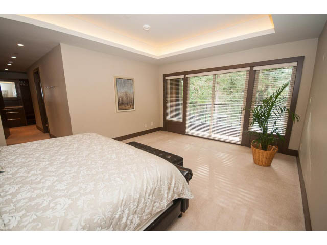 Spacious bedroom with large windows, hardwood floors, and a cozy bed setup. - 5070 Marine Drive, West Vancouver