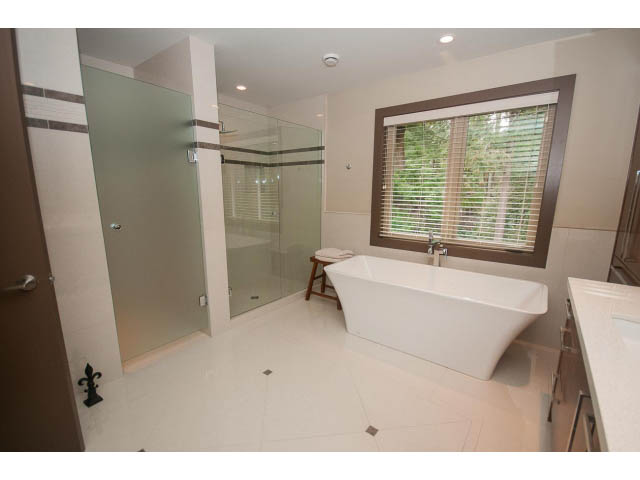 Spacious bathroom with large glass shower, white countertops, and a window with blinds. - 5070 Marine Drive, West Vancouver