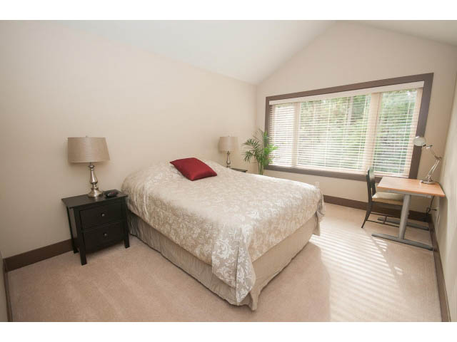 Bright bedroom with a large window, desk, and floral bedding. - 5070 Marine Drive, West Vancouver