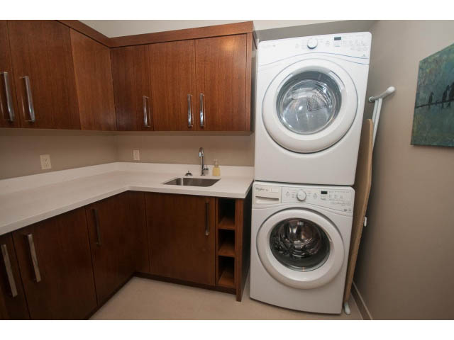 Laundry room with white appliances, wooden cabinets, and countertop. - 5070 Marine Drive, West Vancouver