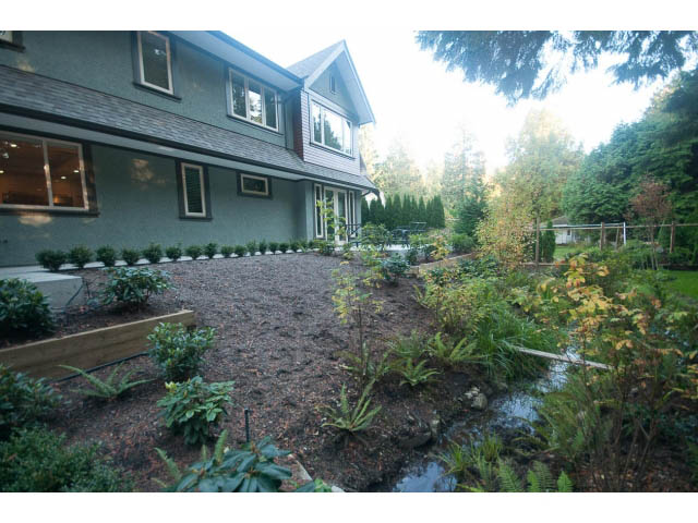 Spacious backyard with a pond and lush greenery, surrounded by trees. - 5070 Marine Drive, West Vancouver
