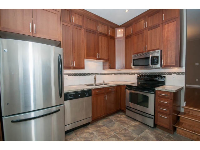 Bright kitchen with stainless steel appliances and granite countertops, showcasing a modern and spacious design.