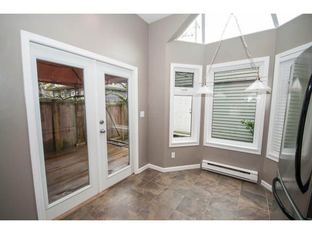 Bright sunroom with large sliding glass doors, hardwood floors, and a view of the backyard. - 1962 West 11th Ave, Vancouver West Side