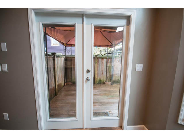 Bright living room with sliding glass doors leading to a patio and umbrella. - 1962 West 11th Ave, Vancouver West Side
