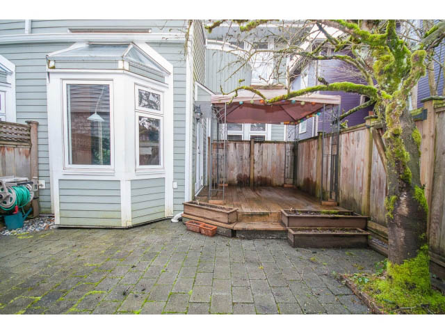 Furnished patio with stone paving and wooden deck, surrounded by greenery. - 1962 West 11th Ave, Vancouver West Side