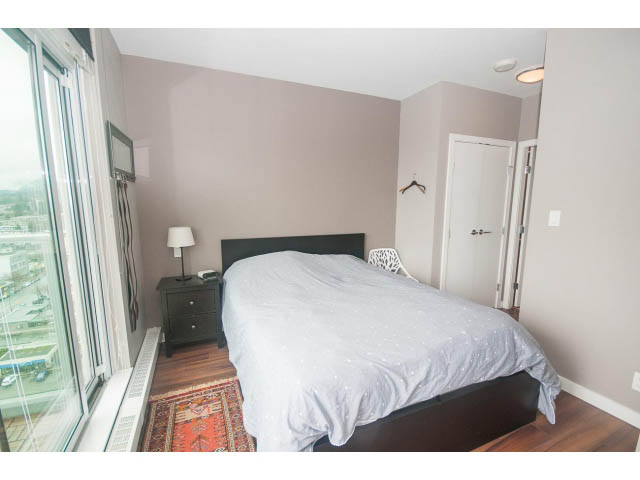 Bright bedroom with hardwood floors, city view, and a cozy bed setup. - 1702 - 135 East 17th Street, North Vancouver