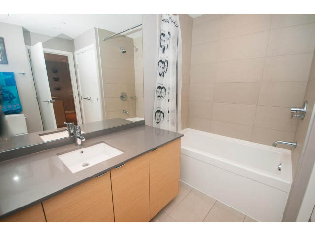 Bright bathroom with modern sink, large mirror, and bathtub. - 1702 - 135 East 17th Street, North Vancouver