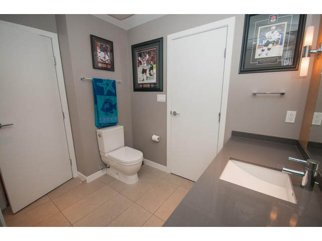 Bathroom with modern sink, framed sports memorabilia, and a toilet. - 1702 - 135 East 17th Street, North Vancouver