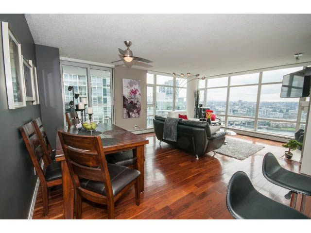 Furnished dining and living area with hardwood floors, city view, and modern decor. - 2706 -198 Aquarius Mews, Vancouver Downtown