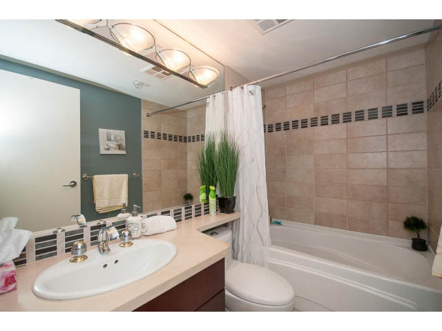 Furnished bathroom with beige countertops, white sink, and tiled walls. - 2706 -198 Aquarius Mews, Vancouver Downtown