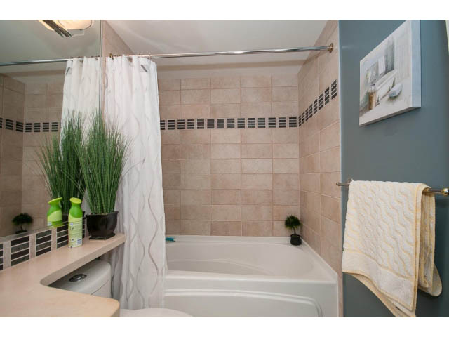 Furnished bathroom with beige tiles, modern fixtures, and a large plant. - 2706 -198 Aquarius Mews, Vancouver Downtown
