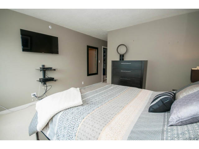 Furnished bedroom with a large bed, patterned bedding, and a mounted TV. - 2706 -198 Aquarius Mews, Vancouver Downtown