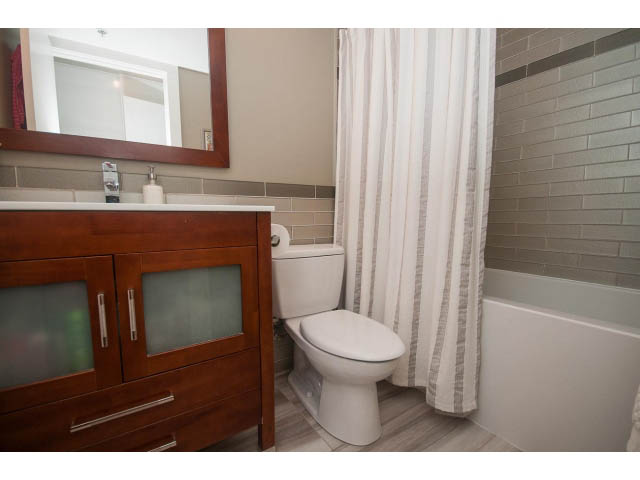 Bright bathroom with wooden vanity, white toilet, and striped shower curtain. - 1203 - 1188 Richards, Vancouver Downtown