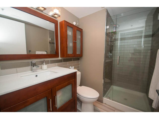 Furnished bathroom with modern sink, frosted glass cabinets, and walk-in shower. - 1203 - 1188 Richards, Vancouver Downtown