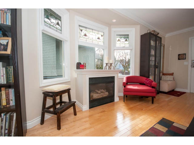 Bright living room with hardwood floors, red couch, and large bay windows. - 3 - 2535 West 6th Ave, Vancouver West Side