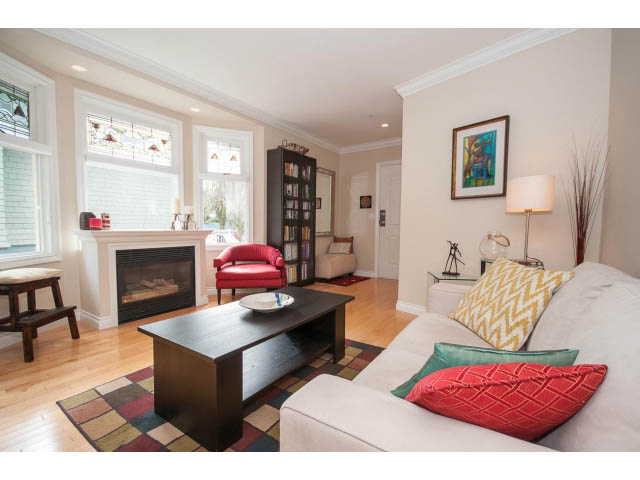 Bright living room with hardwood floors, colorful pillows, and a cozy fireplace. - 3 - 2535 West 6th Ave, Vancouver West Side