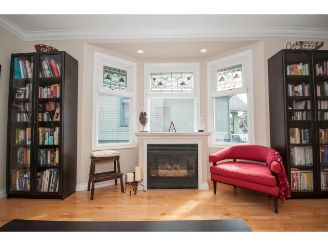 Bright living room with hardwood floors, bookshelves, and red furniture. - 3 - 2535 West 6th Ave, Vancouver West Side