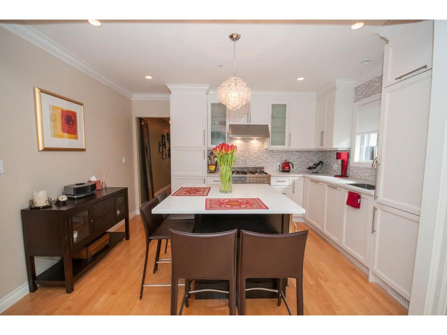 Bright kitchen with white cabinets, red accents, and hardwood floors. - 3 - 2535 West 6th Ave, Vancouver West Side