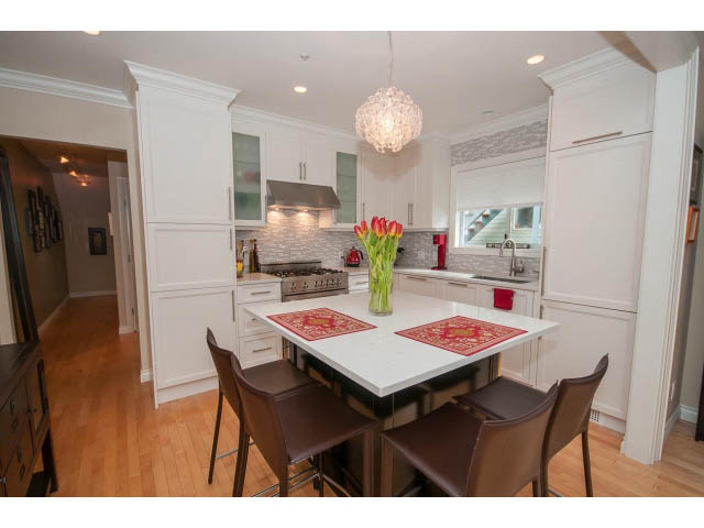 Bright kitchen with white cabinetry, hardwood floors, and a modern chandelier. - 3 - 2535 West 6th Ave, Vancouver West Side