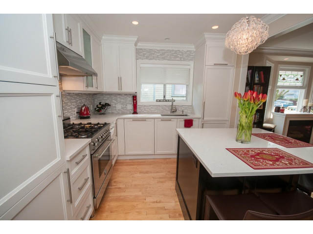 Bright kitchen with white cabinetry, hardwood floors, and a city view. - 3 - 2535 West 6th Ave, Vancouver West Side