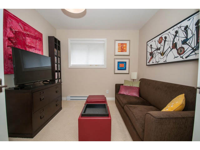 Furnished living room with modern art, brown sofa, red coffee table, and flat-screen TV. - 3 - 2535 West 6th Ave, Vancouver West Side