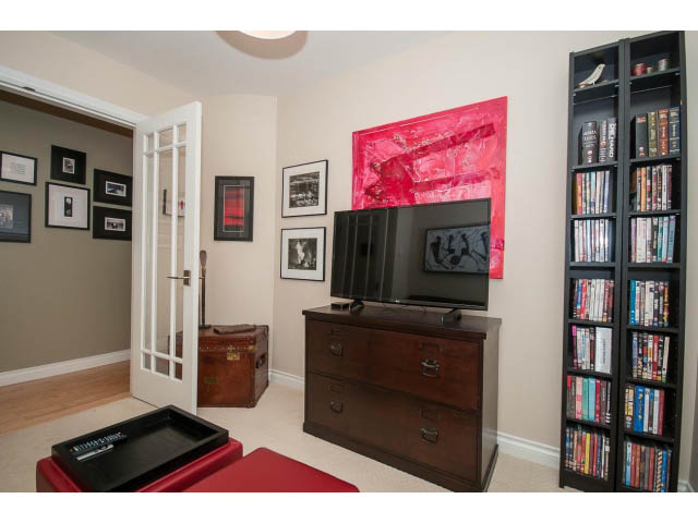Furnished den with wooden furniture, bookshelves, and a red accent wall. - 3 - 2535 West 6th Ave, Vancouver West Side