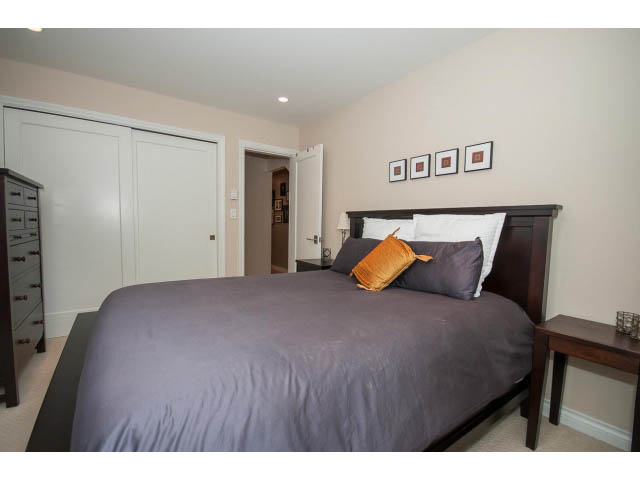 Furnished bedroom with a neatly made bed, dark wood headboard, and framed artwork on the wall. - 3 - 2535 West 6th Ave, Vancouver West Side