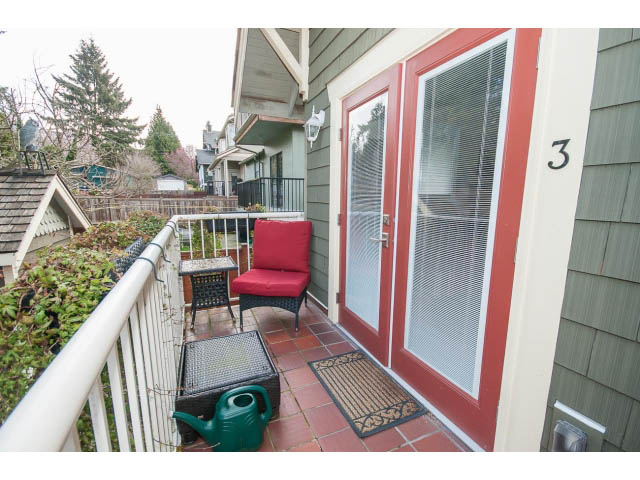 Furnished balcony with red furniture, greenery, and a city view. - 3 - 2535 West 6th Ave, Vancouver West Side