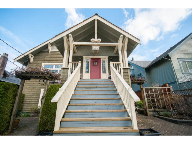 Bright front porch with wooden steps and red door, surrounded by greenery. - 3 - 2535 West 6th Ave, Vancouver West Side